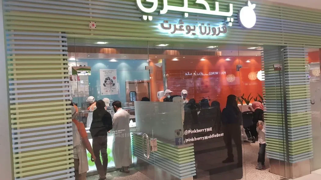 A completed Pinkberry unit with bilingual signage above a fully glazed shopfront and a lit service counter inside.